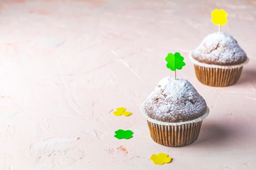 Tasty delicious homemade muffins on light pink living coral stone concrete surface with holiday attributes, copy space. Beautiful sweet food concept for Saint Patrick day.