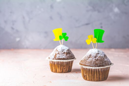 Tasty delicious homemade muffin on light pink living coral stone concrete surface with knitting hearts, copy space. Sweet food for Saint Patrick day.