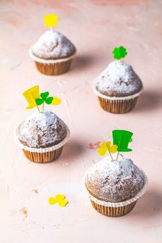 Tasty delicious homemade muffin on light pink living coral stone concrete surface with knitting hearts, copy space. Sweet food for Saint Patrick day.