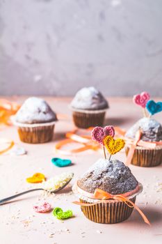 Tasty delicious homemade muffin on light pink living coral stone concrete surface with knitting hearts, copy space. Sweet food for valentines day.