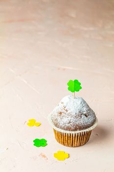 Tasty delicious homemade muffin on light pink living coral stone concrete surface with knitting hearts, copy space. Sweet food for Saint Patrick day.