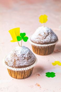 Tasty delicious homemade muffins on light pink living coral stone concrete surface with holiday attributes, copy space. Beautiful sweet food concept for Saint Patrick day.