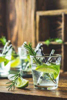 Fresh cocktail with lime, ice and rosemary, mojito cocktail in a bur on a rustic table, selective focus, shallow depth of the field.