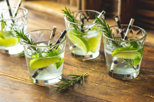 Fresh cocktail with lime, ice and rosemary, mojito cocktail in a bur on a rustic table, selective focus, shallow depth of the field.