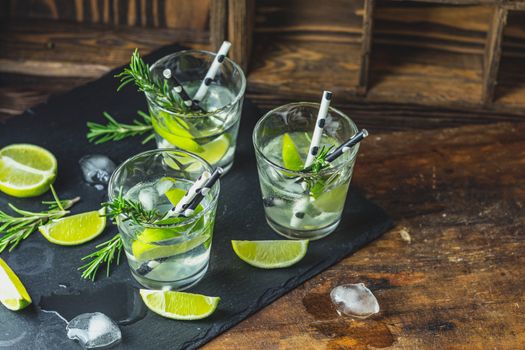 Fresh cocktail with lime, ice and rosemary, mojito cocktail in a bur on a rustic table, selective focus, shallow depth of the field.