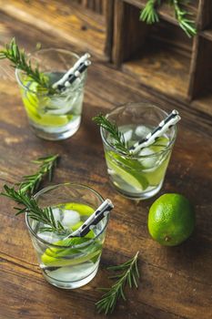 Fresh cocktail with lime, ice and rosemary, mojito cocktail in a bur on a rustic table, selective focus, shallow depth of the field.