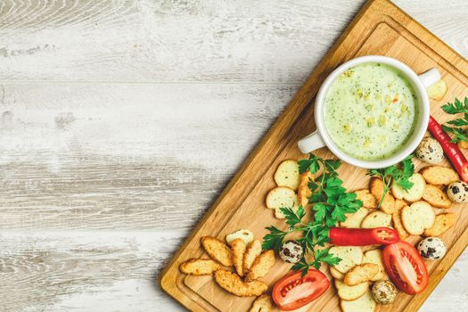 Concept of healthy vegetable and legume soups. Vegetables soup with carrot, eggs and chicken, mushroom cream soup with herbs and crackers and ingredients. Top view on the background of a light gray wooden board, copy space.