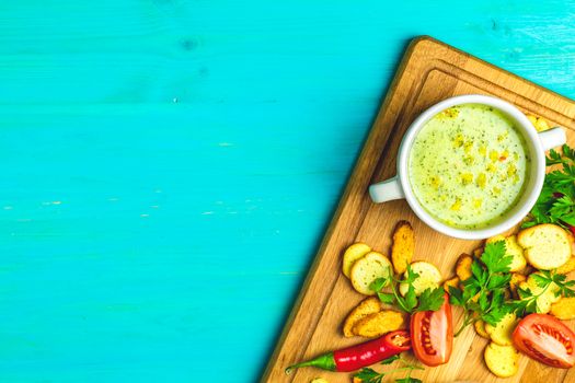 Concept of healthy vegetable and legume soups. Vegetables soup with carrot, eggs and chicken, mushroom cream soup with herbs and crackers and ingredients. Top view on the a blue turquoise wooden board