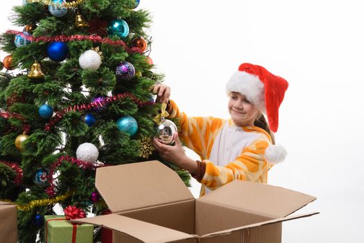 Girl hangs a Christmas ball on the Christmas tree