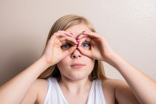Girl looking through her fingers as pretend binoculars