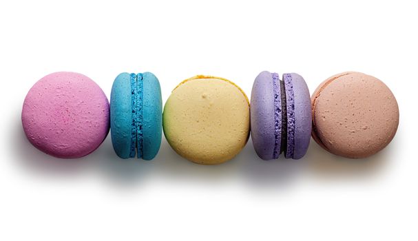 Five multicolored macaroon in row on white background
