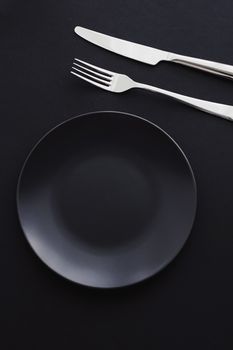 Empty plates and silverware on black background, premium tableware for holiday dinner, minimalistic design and diet concept