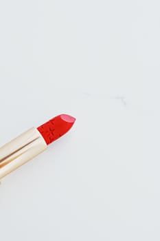 Luxury lipstick in a golden tube on white marble background, make-up and cosmetics concept