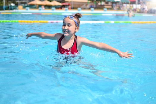 Young girl splashing in the pool on a sunny day