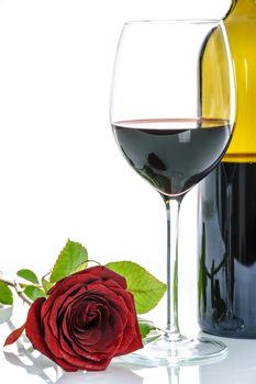 Beautiful red rose and wineglass of red wine and a bottle on a white background.