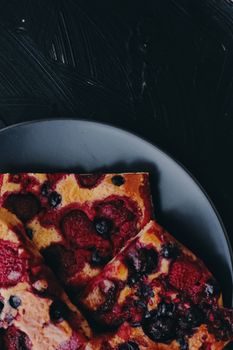 Berry pie on black plate, rustic homemade food with organic ingredients on black background