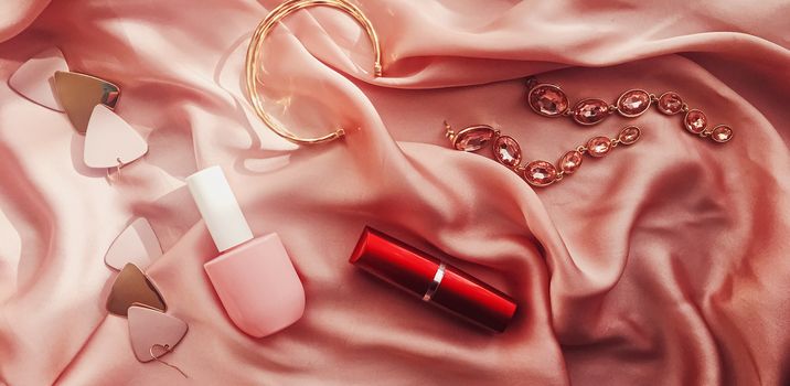 Fashionable and stylish accessories, jewelry and make-up products on pink silk background, beauty and fashion concept