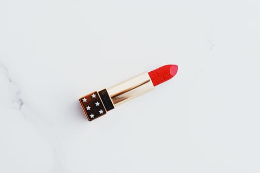 Luxury lipstick in a golden tube on white marble background, make-up and cosmetics concept