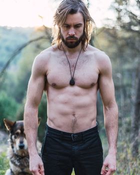 Portrait of a bearded young man with his old dog behind him