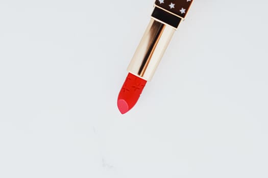 Luxury lipstick in a golden tube on white marble background, make-up and cosmetics concept