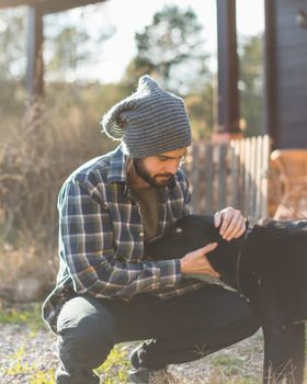 Portrait of a bearded man with his old dog and a beautiful sunset on the mountain