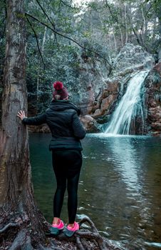 Adult woman standing in front of waterfall and enjoying the view at Kocacay Deresi, Antalya, Turkey.