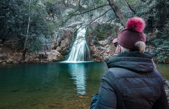 Adult woman standing in front of waterfall and enjoying the view at Kocacay Deresi, Antalya, Turkey.