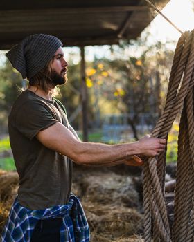 Portrait of young bearded man taking the rope with beautiful sunlight