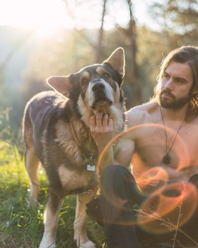 Portrait of a bearded man with his old dog and a beautiful sunset on the mountain