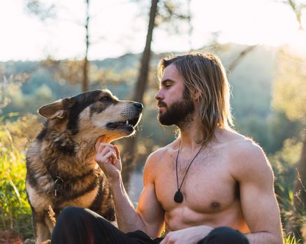 Portrait of a bearded man with his old dog and a beautiful sunset on the mountain