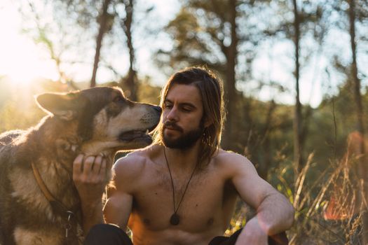 Portrait of a bearded man with his old dog and a beautiful sunset on the mountain
