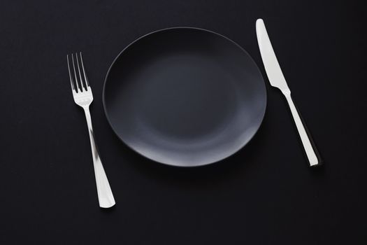 Empty plates and silverware on black background, premium tableware for holiday dinner, minimalistic design and diet concept