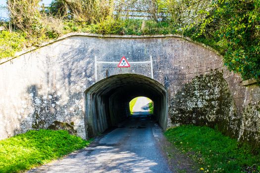 Old brick tunnel carrying narrow road under railway line