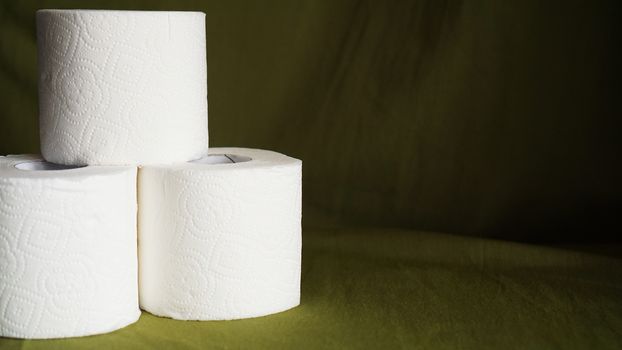 Toilet paper is consider a must item during crisis. Tissue rolls on dark green background for copyspace