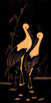 Two cranes stand in a swamp. Painting on a wooden plank.