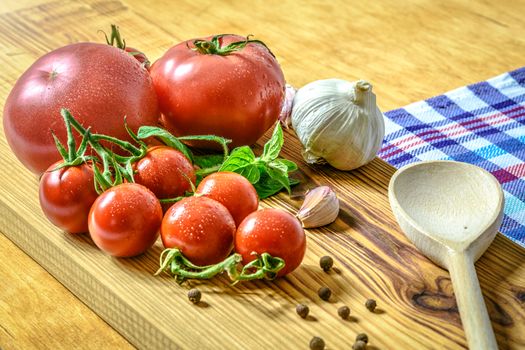 Popular ingredients to prepare a meal: tomatoes, basil, garlic, pasta and pepper on wood background  