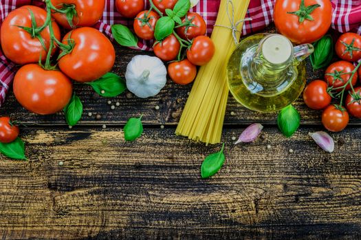 Overhead shot of the classic ingredients of Italian cuisine: spaghetti, basil, garlic, olive oil, pepper on a wooden vintage table