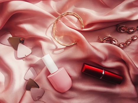 Fashionable and stylish accessories, jewelry and make-up products on pink silk background, beauty and fashion concept