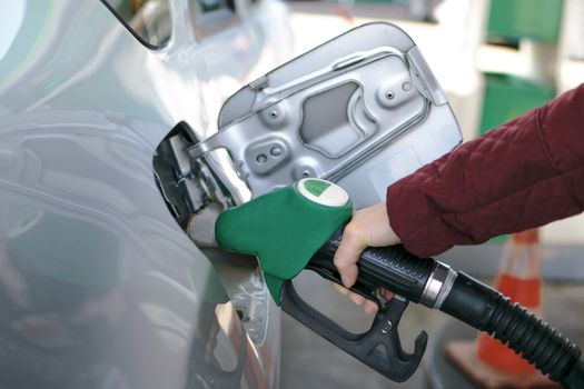 Female hand refilling the car with fuel at petrol station.