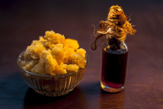 Close up of glass cup full of raw jaggery or gud or palm jaggery and its extracted oil in a glass bottle used for oil pulling in ayurvedic dental treatment. Horizontal shot.