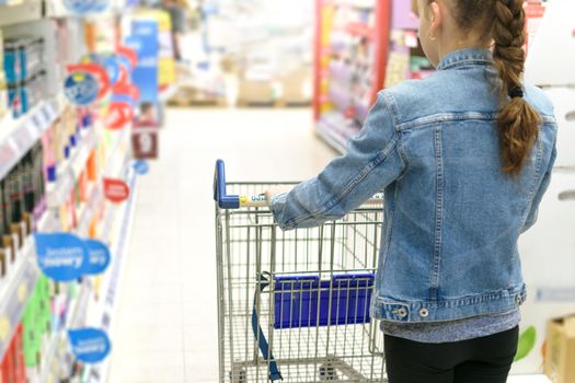 Girl pushing empty shopping cart in a supermarket