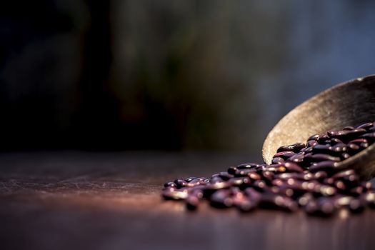 Close up of raw kidney beans on brown colored surface in a clay bowl with a spotlight on it. Horizontal shot.