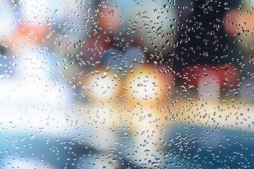 Raindrops on a car window with beautifully blurred background of street traffic lights