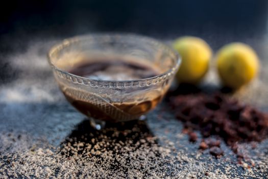 All-purpose ayurvedic salt face mask on the black wooden surface consisting of salt, rock salt, lemon juice, and honey. The face mask as well as a face pack. Horizontal shot.