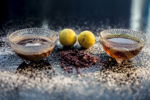 All-purpose ayurvedic salt face mask on the black wooden surface consisting of salt, rock salt, lemon juice, and honey. The face mask as well as a face pack. Horizontal shot.