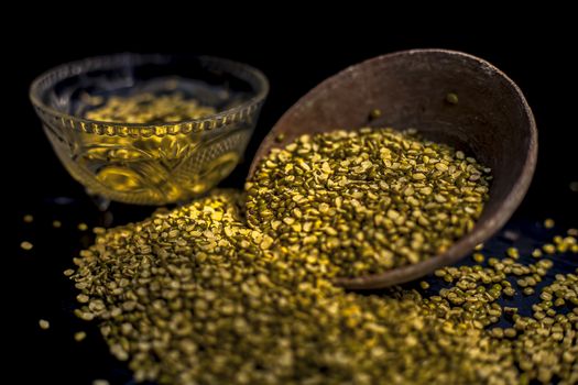 Close shot of mung bean or moong dal in a clay bowl along with some water and moong dal well mixed on a black glossy surface. Horizontal shot with Rembrandt lighting technique.