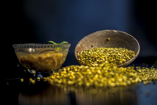 Close shot of mung bean or moong dal in a clay bowl along with some water and moong dal well mixed on a black glossy surface. Horizontal shot with Rembrandt lighting technique.