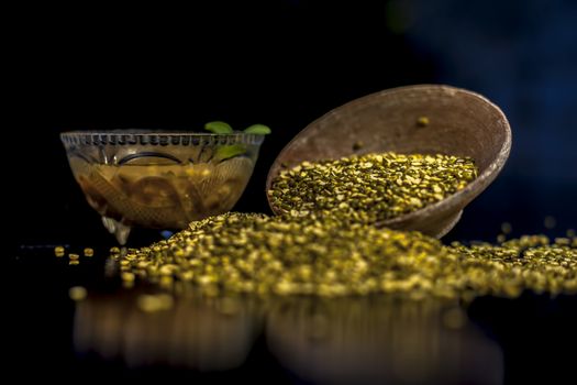 Close shot of mung bean or moong dal in a clay bowl along with some water and moong dal well mixed on a black glossy surface. Horizontal shot with Rembrandt lighting technique.