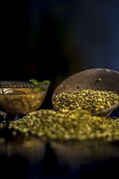 Close shot of mung bean or moong dal in a clay bowl along with some water and moong dal well mixed on a black glossy surface.Vertical shot with Rembrandt lighting technique.
