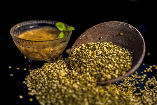 Close shot of mung bean or moong dal in a clay bowl along with some water and moong dal well mixed on a black glossy surface. Horizontal shot with Rembrandt lighting technique.